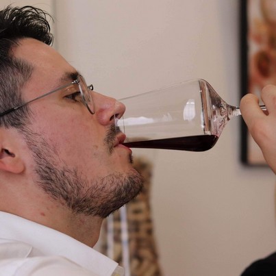 Homme de profil dégustant un verre de vin rouge lors d'un cours d'œnologie à Sensation Vin à Beaune pour la Fête des Pères.